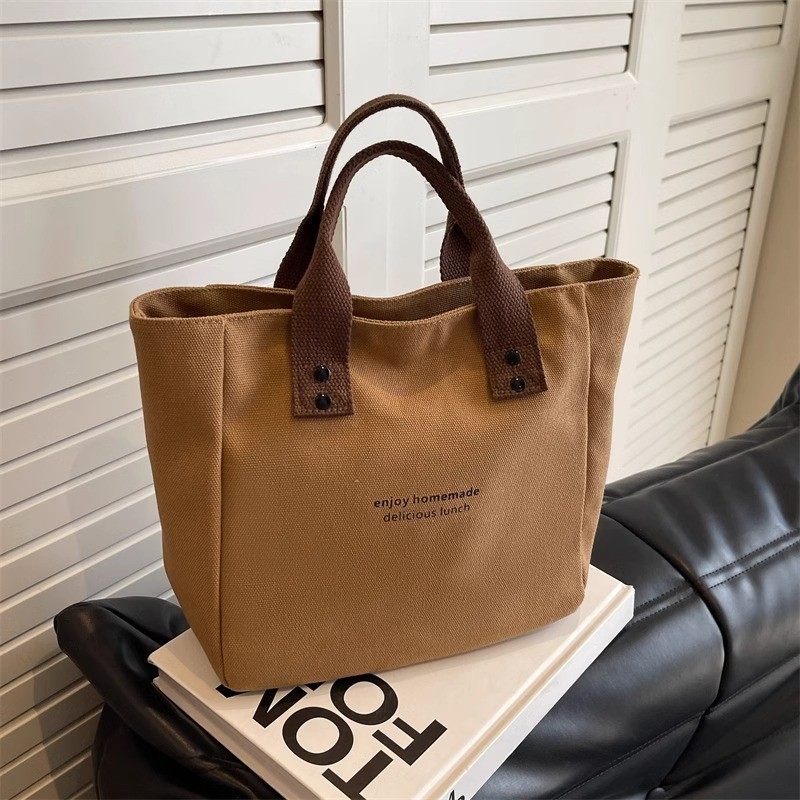 Brown tote bag with text on a black surface and white background